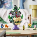 Colorful Lego Sculpture on a Purple Pedestal Surrounded by Small Lego Figures on a Wooden Table