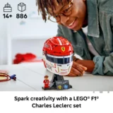 Lego Ferrari F1 Helmet Model on a Display Stand with a Small Minifigure While a Person Smiles in the Background
