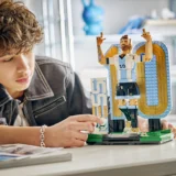 Young Person Building a Large Lego Figure of a Man with Blue and yellow Wings on a White Table