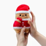 Small Plush Santa Claus Toy Being Held Between Two Hands Against a White Background Red Suit with White Trim informational