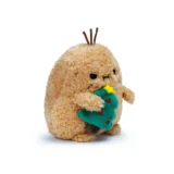 a Fuzzy Tan Plush Creature Hugging a Small Green Christmas Tree with a Yellow Star and Red Ornaments