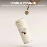 White Insulated Travel Tumbler with a Woven Strap and a Cartoon Hat wearing Logo Suspended in Midair Against a Soft Gradient