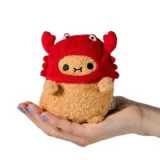 Small Plush Toy Held in an Open Hand Wearing a Red Crab shaped Hood with Big Eyes on Top