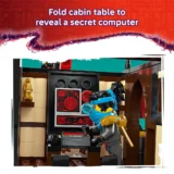 Lego Minifigure with Blue Scarf at a Control Console Inside a Cabin Revealing a Red lit Secret Computer Screen Behind a Foldable Table